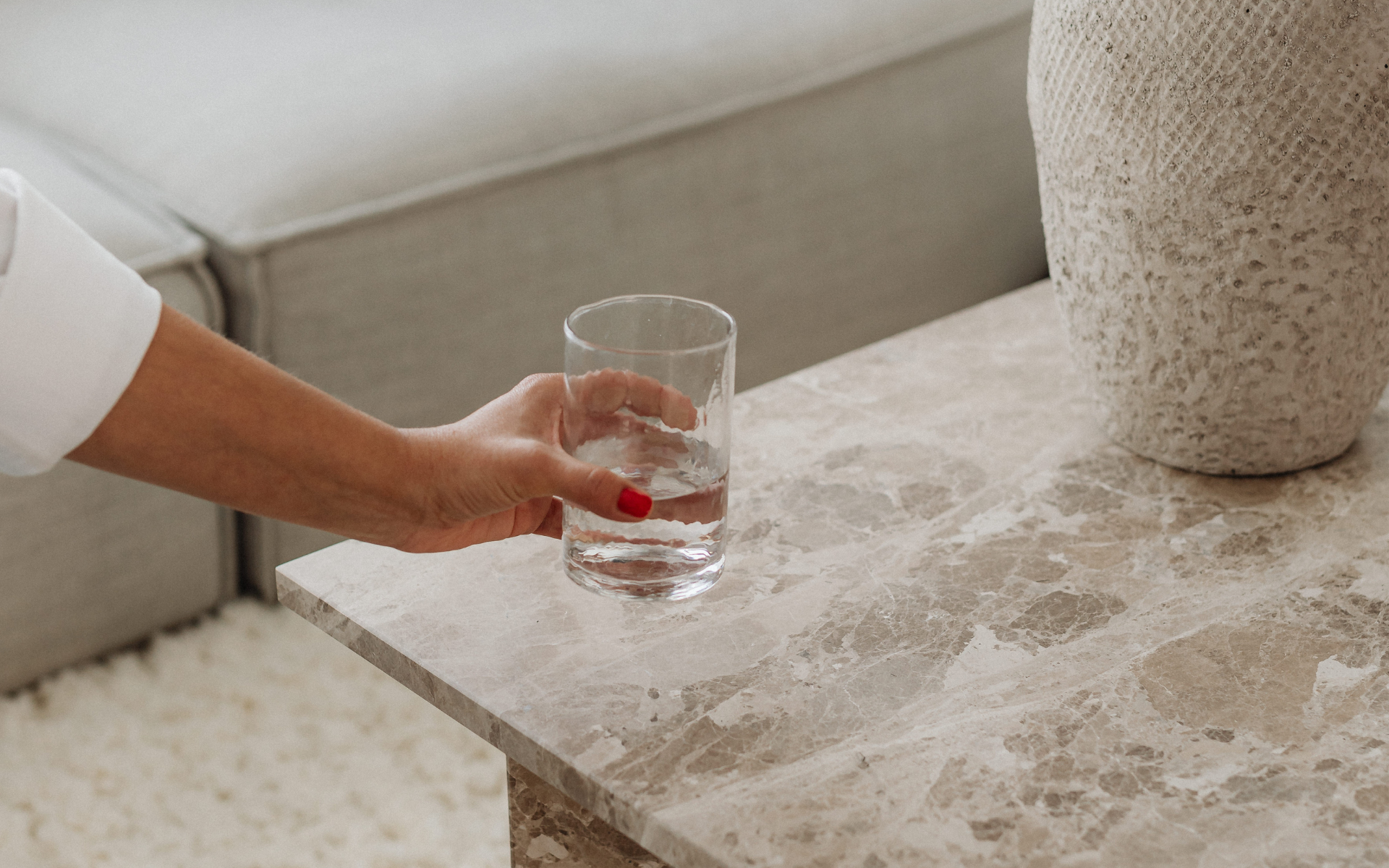 Hand holding a glass of filtered water in a calm low-toxin home environment
